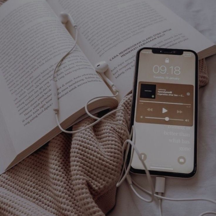 A cozy morning scene with a book, a phone showing a Spotify playlist, and soft beige blanket in natural light — calm, slow-living atmosphere that evokes gentle focus and warmth.