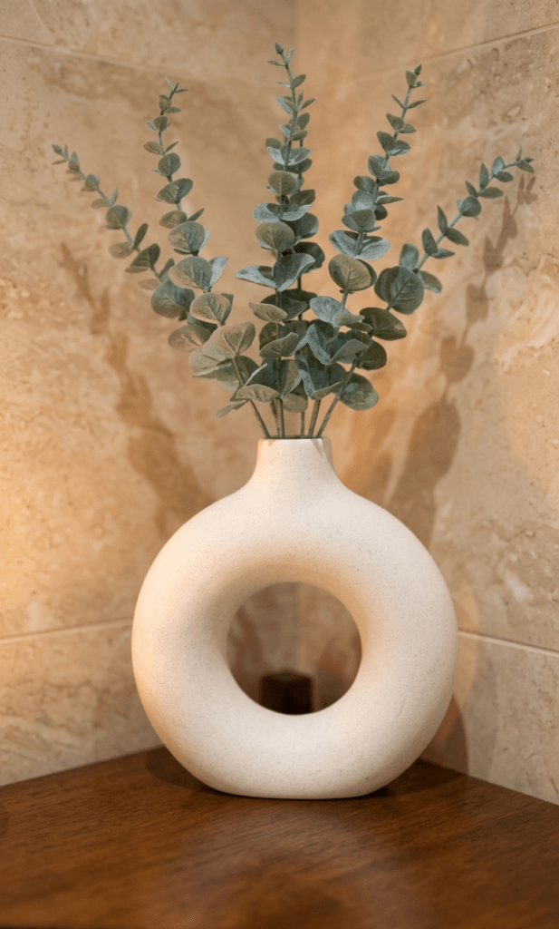 modern donut vase with eucalyptus stems creating single focal point in minimalist bathroom styling