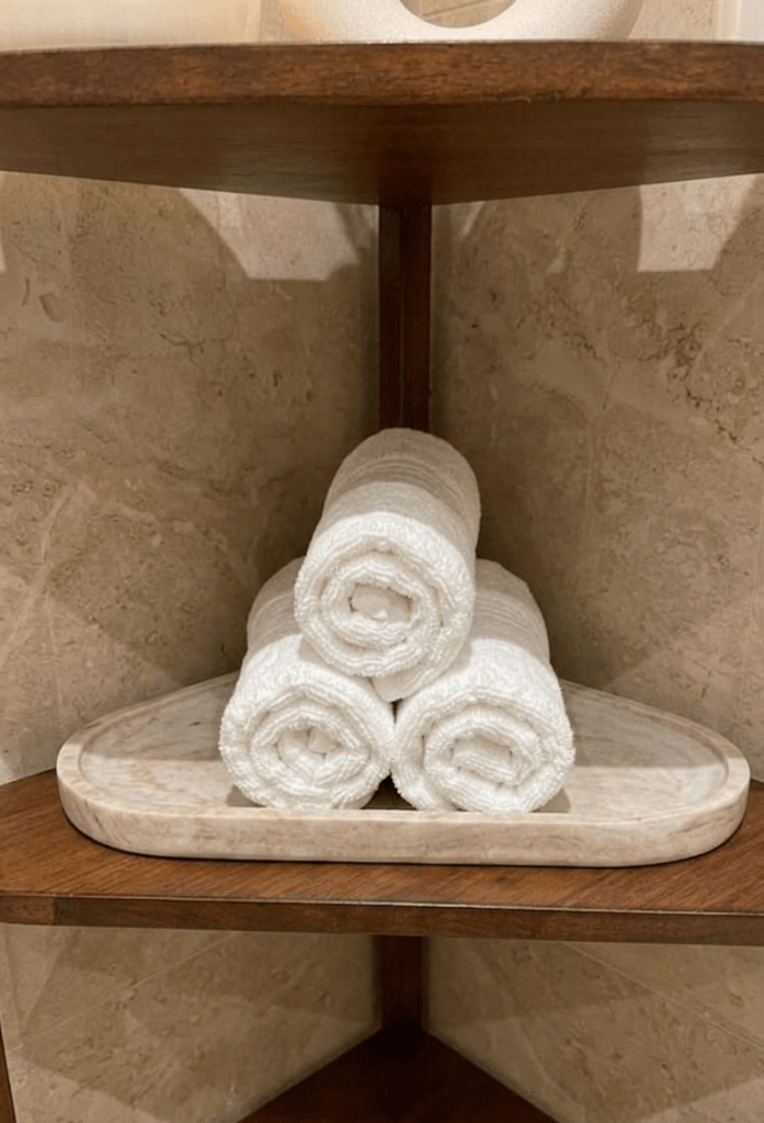 rolled white towels on wooden tray creating organized bathroom vanity base zone with minimal clutter aesthetic