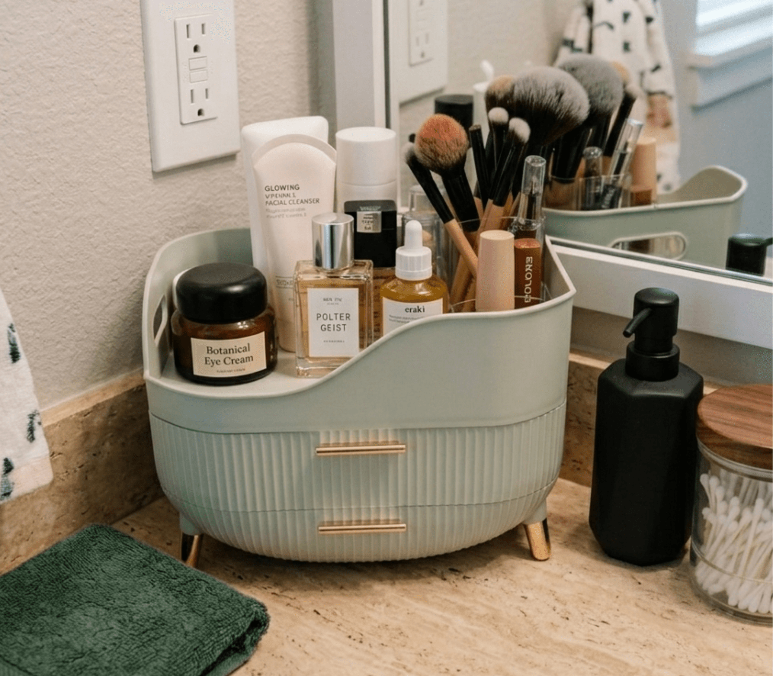 Minimal sage green bathroom counter organizer with drawers holding skincare, makeup brushes, perfume, and beauty products on a calm neutral vanity countertop.