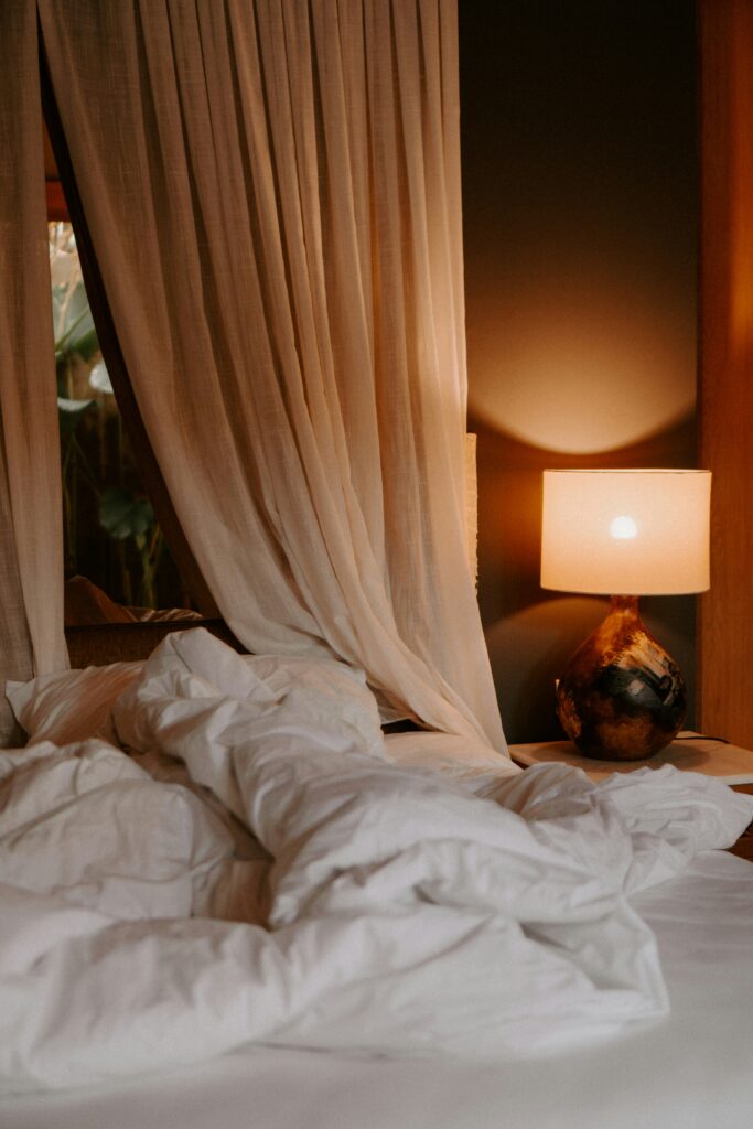 Cozy bedside lamp with warm ambient light, soft curtains, and relaxed hotel-inspired bedroom styling