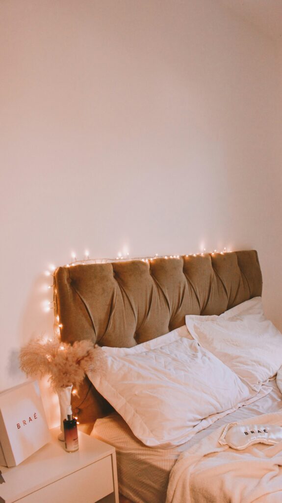 Cozy bedroom with warm string lights, upholstered headboard, and soft neutral bedding