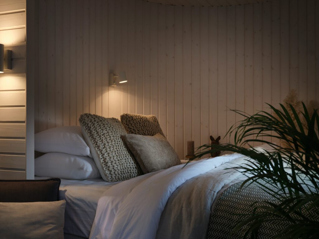 Cozy bedroom with low warm lighting, soft bedding, and calming evening light below eye level