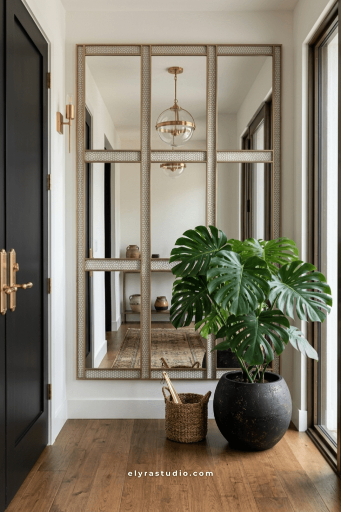 Bright modern entryway with oversized wall mirrors, black doors, brass accents, and indoor plants.